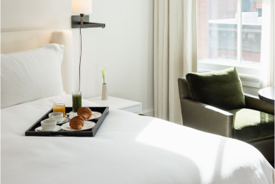 Room service tray on a neatly made bed inside of the mercer hotel