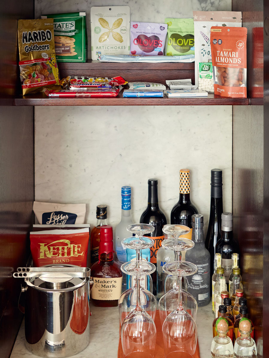 View of the complimentary minibar with snacks on the top shelf, and tons of drink options on a marble counter