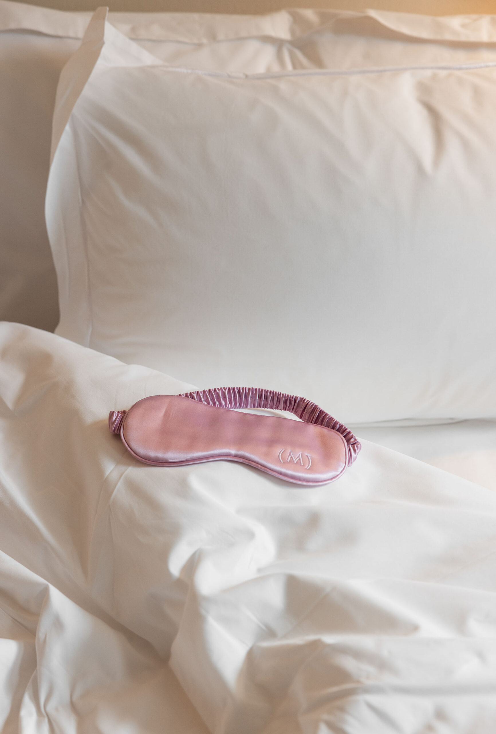 A sleep eye-mask on white turned down covers