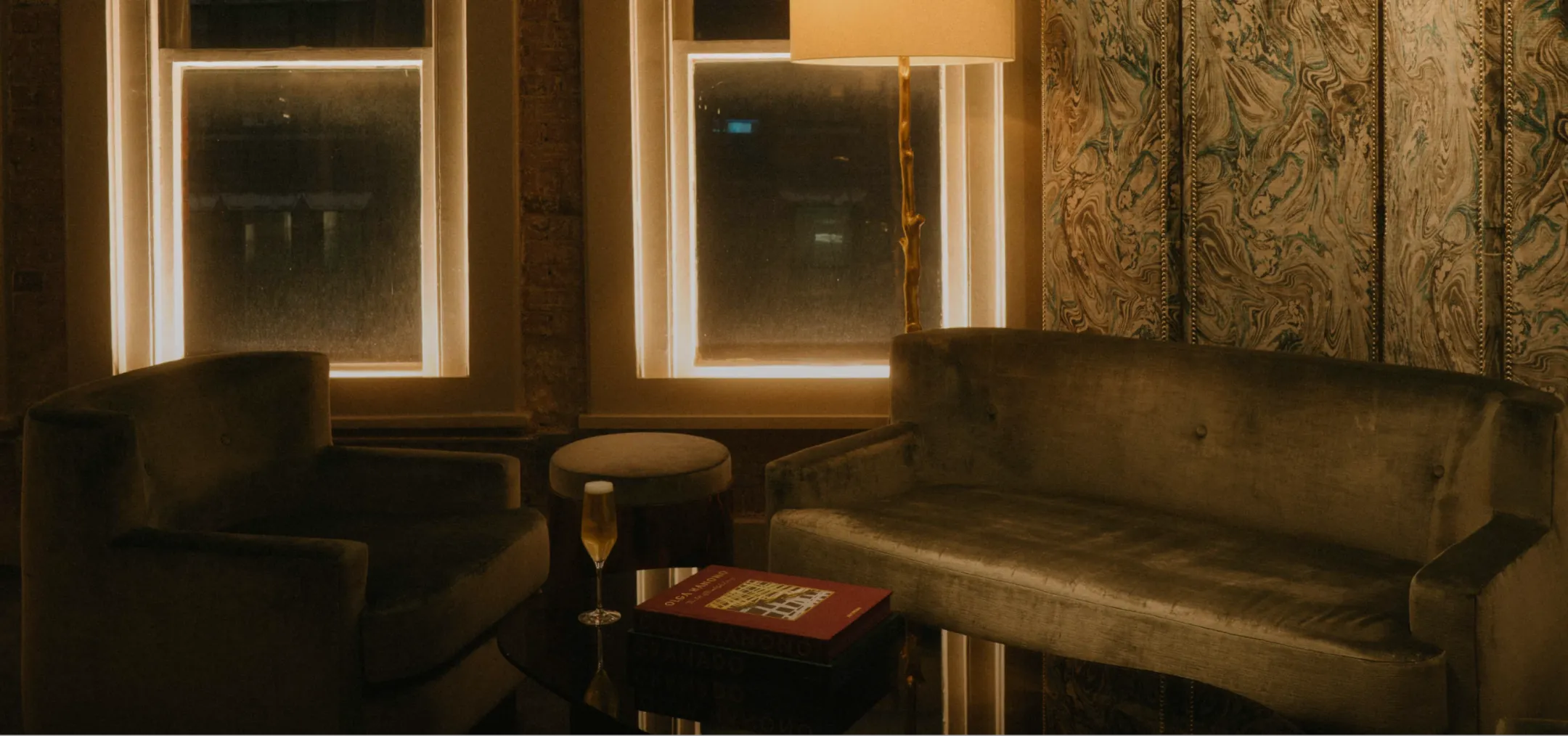 A private seating area inside the mercer hotel with dim floor lighting and illuminated windows at night.